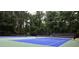 View of two outdoor tennis courts with blue and green surfaces and mature trees surrounding them at 340 Channings Lake Dr, Lawrenceville, GA 30043