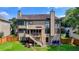 Backyard featuring a two-story home, stairs leading to a deck, level lawn, and a wooden fence at 350 River Walk Ter, Johns Creek, GA 30024