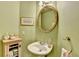 Charming powder room featuring a pedestal sink, decorative mirror, and soft green walls at 350 River Walk Ter, Johns Creek, GA 30024
