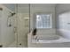 Bright bathroom featuring a glass enclosed shower and a luxurious soaking tub beneath a sunny window at 350 River Walk Ter, Johns Creek, GA 30024