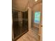 Bathroom featuring glass shower with dark tile, wood floor, and a window at 12 Barrington Ct, Sharpsburg, GA 30277