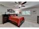 Cozy bedroom featuring a dark wooden bed frame with red bedding, ceiling fan, and decorative wall art at 1595 Northcliff Trce, Roswell, GA 30076