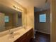 Bathroom featuring a large mirror, dual sinks and a tub with shower; complemented by wood-look vinyl floors at 425 Bell Flower Trl, Locust Grove, GA 30248