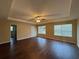 Spacious living room with tray ceiling, ceiling fan, wood-look vinyl flooring, and several windows for natural light at 425 Bell Flower Trl, Locust Grove, GA 30248
