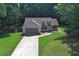 Aerial view of a charming home with a well-manicured lawn, driveway, and mature trees at 106 Kimbell Farm Dr, Locust Grove, GA 30248