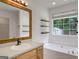 Light and bright bathroom with a large framed mirror and soaking tub beneath the window at 106 Kimbell Farm Dr, Locust Grove, GA 30248