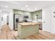 Open kitchen with island, stainless steel appliances, and green cabinets, adjacent to hallway at 106 Kimbell Farm Dr, Locust Grove, GA 30248