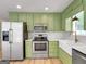 Modern kitchen with stainless steel appliances, farmhouse sink, and updated green cabinetry at 106 Kimbell Farm Dr, Locust Grove, GA 30248