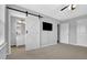 Bedroom with a modern barn door leading to bathroom, TV, and neutral carpet at 4445 Hager Ct, Cumming, GA 30040