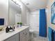 Well-lit bathroom with a vanity, toilet, and a shower-tub combination with a blue shower curtain at 2348 Logan Ne Cir, Brookhaven, GA 30319