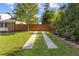 Scenic backyard featuring a lush lawn and driveway bordered by mature trees and a privacy fence at 425 Houze Way, Roswell, GA 30076