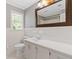 Bright bathroom featuring white tiled walls, a large framed mirror, and a white vanity with storage at 425 Houze Way, Roswell, GA 30076