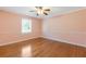 This bedroom has hardwood floors, light pink paint, a ceiling fan, and a window with natural light at 425 Houze Way, Roswell, GA 30076