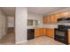 Traditional kitchen with wood cabinets, black appliances, and neutral countertop at 7021 New Dale Rd, Rex, GA 30273
