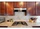 Close up of the kitchen cooktop with granite countertops and a tile backsplash at 3015 Guardian Nw Walk, Kennesaw, GA 30152