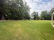 Expansive backyard featuring lush green grass and mature trees offering privacy and a natural setting at 6945 Melody Ridge Rd, Buford, GA 30518