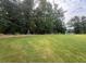 Large grassy backyard with mature trees in the background at 6945 Melody Ridge Rd, Buford, GA 30518