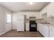 Well-lit kitchen features white cabinets, black appliances, and stylish vinyl flooring at 711 Ashley Ln, Stone Mountain, GA 30087