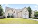 Traditional two-story home with a two-car garage and front lawn under a bright, cloudy sky at 7270 Williamsburg Dr, Riverdale, GA 30274