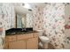 Features a toilet and sink with a black marble countertop, against a floral patterned wall at 7098 Stonington Dr, Atlanta, GA 30328