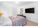 Bright bedroom with a flat screen tv mounted on the wall, carpeted floors, and a bed covered with a purple patterned duvet at 560 Edgehill Pl, Johns Creek, GA 30022