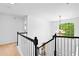 Upstairs hallway with white walls and trim, carpet, staircase, chandelier, and a view from the arched window at 560 Edgehill Pl, Johns Creek, GA 30022