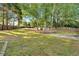 Expansive backyard featuring lush greenery, a firepit area, a stone patio, and mature trees for privacy at 5735 Lake Windsor Pkwy, Buford, GA 30518