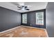 Modern bedroom with hardwood floors, ceiling fan, and natural light from two windows at 5735 Lake Windsor Pkwy, Buford, GA 30518
