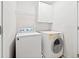 Compact laundry room with modern appliances, a wire rack, and white cabinets at 5340 Harris Creek Dr, Cumming, GA 30040