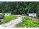 Wide aerial shot of backyard with two sheds, mature trees, and large graveled parking area at 175 Hunters Gln, Fayetteville, GA 30215