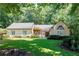 Inviting one-story home featuring a lush front lawn, well-maintained landscaping, and an elegant front door at 1565 Kings Xing, Smoke Rise, GA 30087