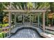 Exterior shot of a pergola with a seat and decorative accents surrounded by greenery at 1565 Kings Xing, Smoke Rise, GA 30087