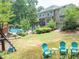 A backyard view with a pool, playset, patio furniture, and lush greenery at 505 Armor Knl, Powder Springs, GA 30127