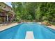 A backyard pool featuring a diving board, patio furniture, lush greenery, and deck at 505 Armor Knl, Powder Springs, GA 30127