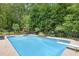 A backyard pool featuring a diving board, patio furniture, lush greenery, a play set, and a deck at 505 Armor Knl, Powder Springs, GA 30127