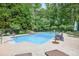 A backyard pool featuring patio furniture, lush greenery, and deck, within a fenced in yard at 505 Armor Knl, Powder Springs, GA 30127