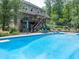 A backyard pool featuring a diving board, patio furniture, lush greenery, and deck at 505 Armor Knl, Powder Springs, GA 30127