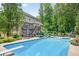 A backyard pool featuring a diving board, patio furniture, lush greenery, and deck at 505 Armor Knl, Powder Springs, GA 30127