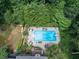 Aerial view of a sparkling in-ground swimming pool surrounded by mature trees and patio furniture at 505 Armor Knl, Powder Springs, GA 30127