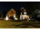 Well-manicured lawn and manicured hedges frame a charming home with a welcoming front porch at night at 5347 Harbury Cv, Suwanee, GA 30024