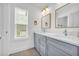 Bright bathroom featuring double sinks with chrome faucets, gray cabinets, stylish mirrors, and a window with blinds at 183 Cleveland # B, Atlanta, GA 30316
