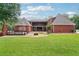 Backyard view of brick home features a deck, fire pit, mature landscaping and plush green grass at 2631 Young Rd, Stone Mountain, GA 30088