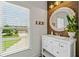 Bright bathroom featuring a modern vanity, round mirror, and a window overlooking the yard at 4875 Churchill Ridge Dr, Cumming, GA 30028