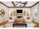 Spacious living room with exposed beams, a stone fireplace, and custom built-in shelving at 4875 Churchill Ridge Dr, Cumming, GA 30028