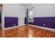Bright bedroom featuring hardwood floors, a window with curtains, a white door, and a purple accent wall at 5022 Anclote Dr, Alpharetta, GA 30022