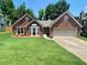 Charming one-story brick home featuring a manicured lawn, bay window, and attached two-car garage at 5022 Anclote Dr, Alpharetta, GA 30022