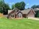 Charming one-story brick home featuring a manicured lawn, bay window, and attached two-car garage at 5022 Anclote Dr, Alpharetta, GA 30022