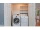 A small laundry room with white washer, dryer, white bi-fold door and wire shelves at 5022 Anclote Dr, Alpharetta, GA 30022