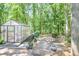 Backyard featuring a greenhouse, patio, and mature trees, perfect for gardening and outdoor enjoyment at 686 Hillwood Ct, Dacula, GA 30019