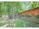 Landscaped backyard featuring a greenhouse, deck, retaining wall with privacy fence and large trees at 686 Hillwood Ct, Dacula, GA 30019